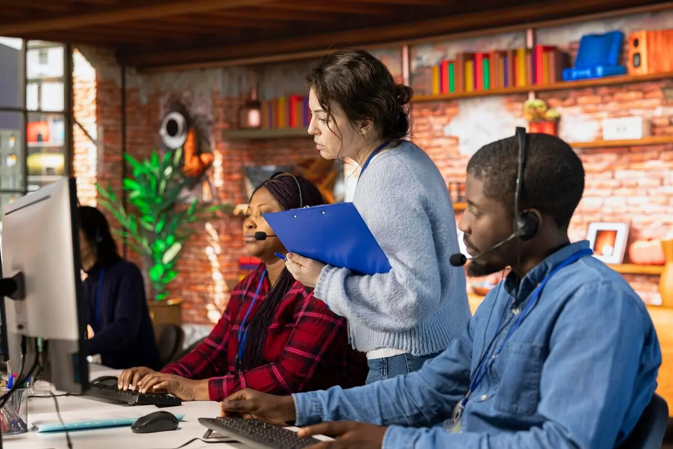 Teamleiter im Callcenter überwacht Agenten am Schreibtisch im Büro, die den Kunden helfen.